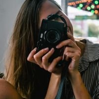 Cliente sonriente tomando una fotografía con cámara profesional en ambiente interior con luz natural. | Diseño Web – SZ Web Design.