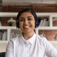 Mujer joven con auriculares, sonriente, trabajando desde casa con fondo de estantería y ambiente profesional. - cliente feliz, atención personalizada, trabajo remoto, experiencia positiva, testimonio real. | Diseño Web – SZ Web Design.