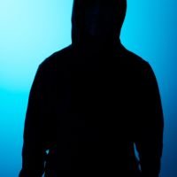 Figura anónima con capucha sobre fondo azul iluminado, representando confidencialidad y seguridad digital. - cliente anónimo, seguridad online, confidencialidad, privacidad, profesionalismo discreto. | Diseño Web – SZ Web Design.