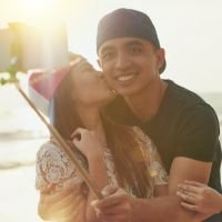 Pareja joven tomándose una selfie en la playa al atardecer, disfrutando el momento con una expresión feliz y relajada. - clientes satisfechos, experiencia positiva, confianza, conexión emocional, testimonio visual. | Diseño Web – SZ Web Design.