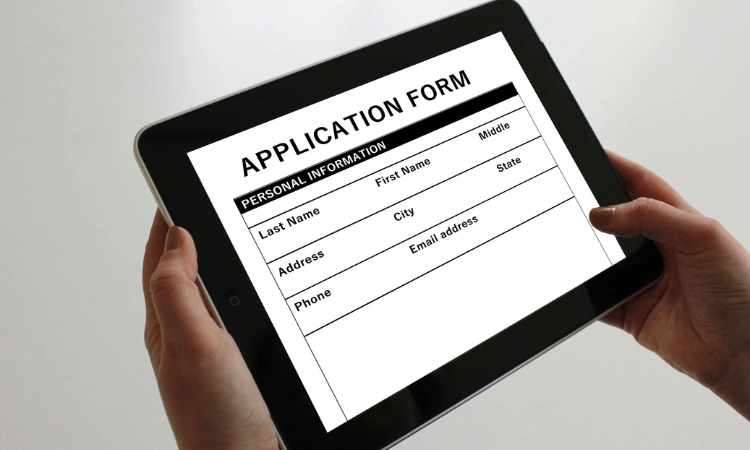 Formulario de aplicación digital mostrado en una tablet sostenida por dos manos.