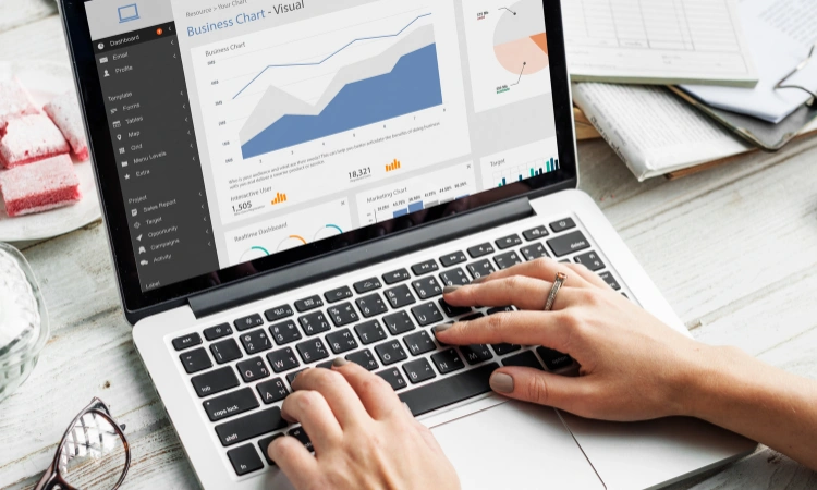 Persona analizando gráficos de métricas empresariales y rendimiento web desde una laptop.