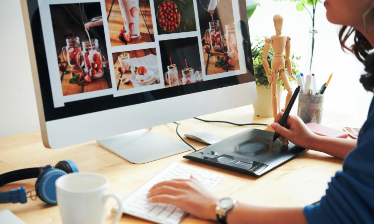 Diseñador gráfico editando fotografías de alimentos en computadora con tableta digital.