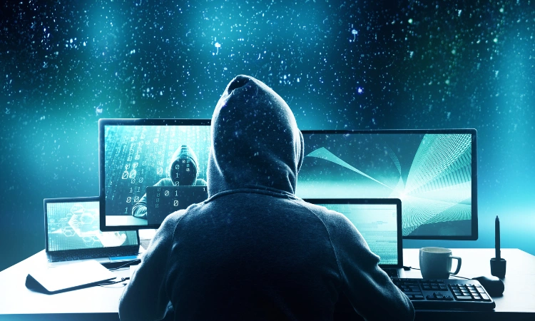 Hacker realizando ciberataque frente a múltiples monitores.
