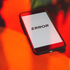 Smartphone con pantalla blanca y mensaje de error, sobre fondo desenfocado de colores intensos.