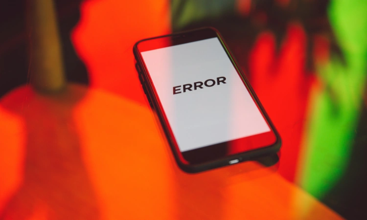 Smartphone con pantalla blanca y mensaje de error, sobre fondo desenfocado de colores intensos.