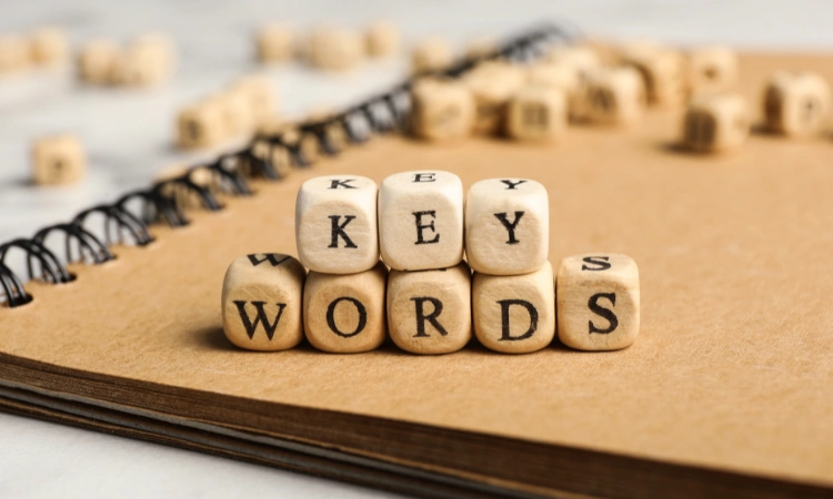 Bloques de madera con letras formando la palabra "keywords" sobre un cuaderno, representando estrategias de palabras clave para SEO.
