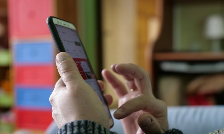 Persona navegando en smartphone desde casa.