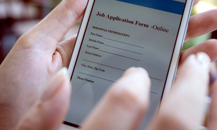 Imagen de una persona completando un formulario de solicitud de empleo en un teléfono móvil, con enfoque en los datos personales y una interfaz digital.